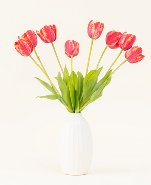 Il bouquet di fiori artificiali in seta Tulipano francese rosso è disposto in un vaso di ceramica bianca, con otto tulipani rossi e gialli con foglie verdi su uno sfondo chiaro.