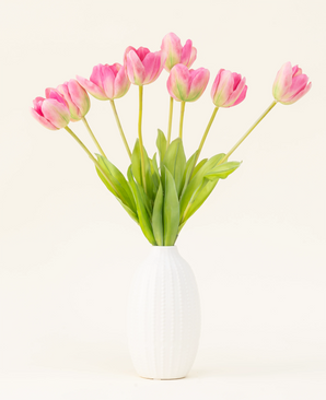 Il bouquet di fiori artificiali in seta Tulipano francese rosa è disposto in un vaso bianco, con tulipani francesi rosa e foglie verdi su un semplice sfondo chiaro.