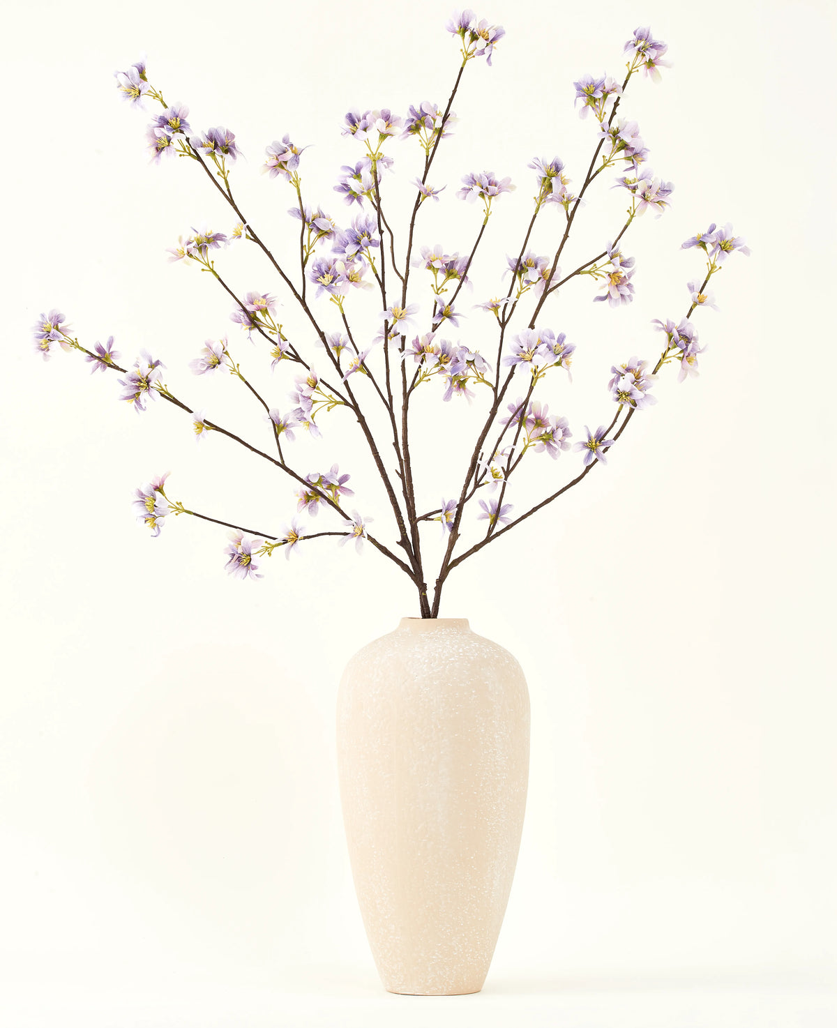 Un vaso alto in ceramica color crema contiene una serie di rami sottili con il testo Bouquet di fiori artificiali in seta Ramo di fiori artificiali viola, su uno sfondo semplice e chiaro.