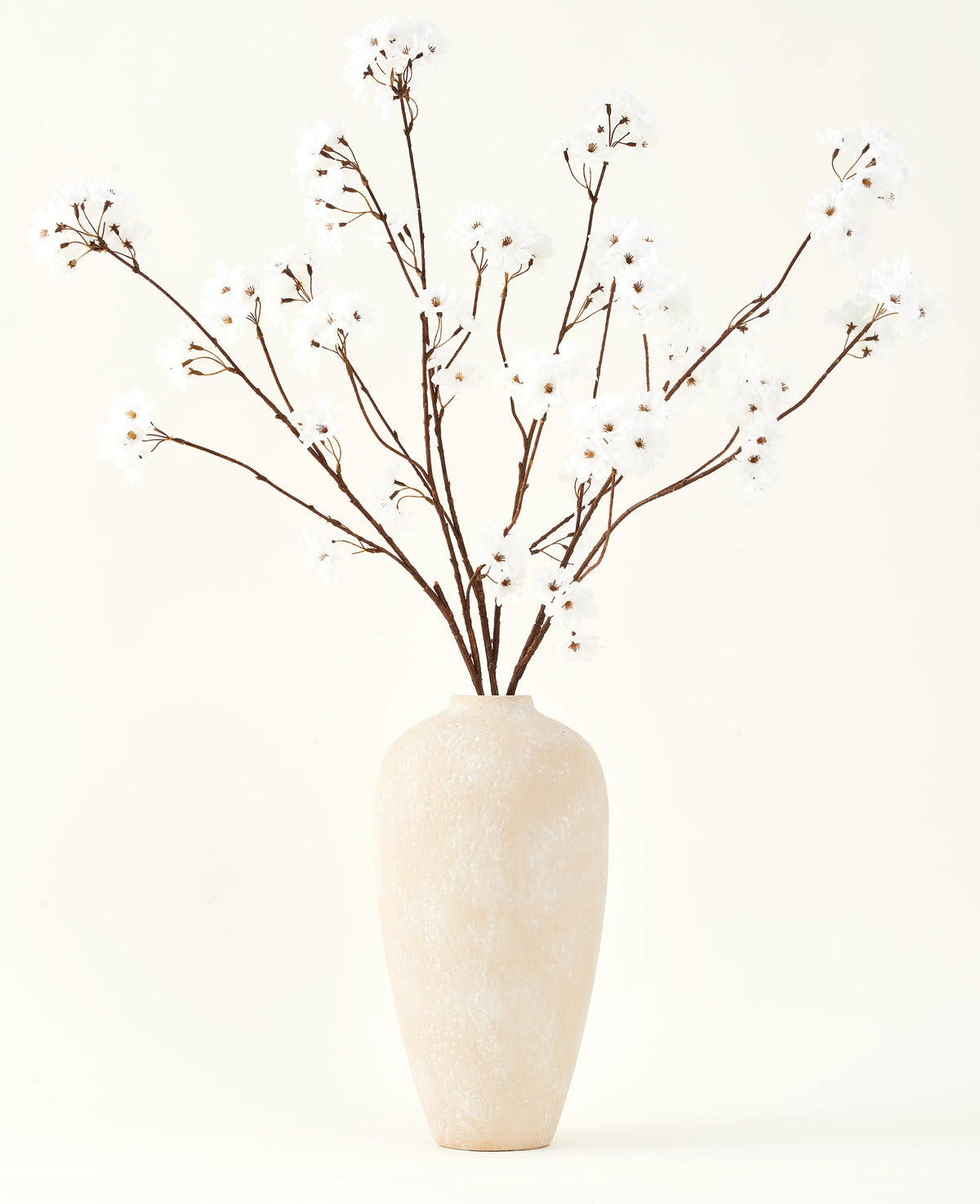 Il bouquet di fiori artificiali Silk Fiore di ciliegio crema 114 cm è alto in un vaso di ceramica beige e porta una decorazione serena in ogni stanza con i suoi delicati rami color crema su uno sfondo chiaro.