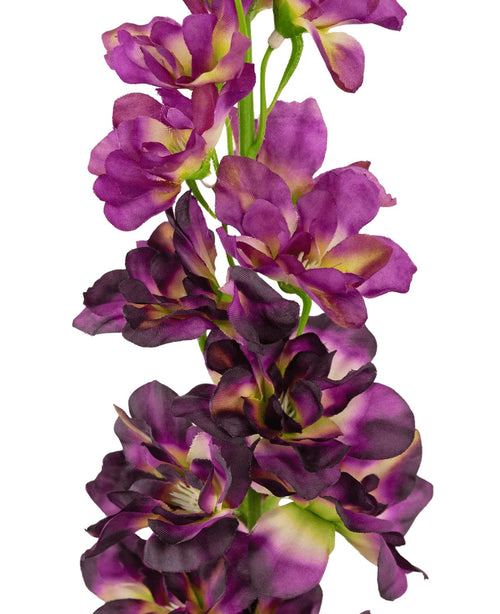 Un primo piano del fiore artificiale Delphinium Purple da 79 cm, un alto stelo artificiale con molteplici fiori viola e viola scuro con un cuore verde e giallo, su sfondo bianco.