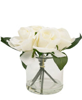 Il bouquet di rose artificiali Real Touch White da 18 cm è un piccolo vaso di vetro con diverse rose artificiali bianche e foglie verdi, splendidamente disposte su un semplice sfondo bianco.