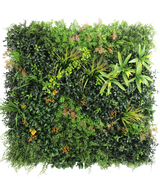 La siepe artificiale Marisa 100x100 cm UV è una parete verde rigogliosa e quadrata con piante dal fogliame misto, felci, accenti giallo-verdi e foglie brunastre sparse su uno sfondo bianco semplice.