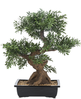 L'albero bonsai artificiale da 70 cm in vaso ha una chioma verde densa e un tronco spesso e contorto, in un vaso rettangolare nero pieno di ciottoli su sfondo bianco.