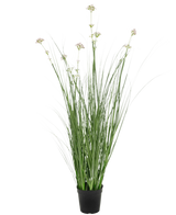 L'erba artificiale, fiore di porro, cipolla, vaso ignifugo da 90 cm ha foglie verdi lunghe e sottili e grappoli di fiori chiari in un vaso nero, su uno sfondo bianco semplice.