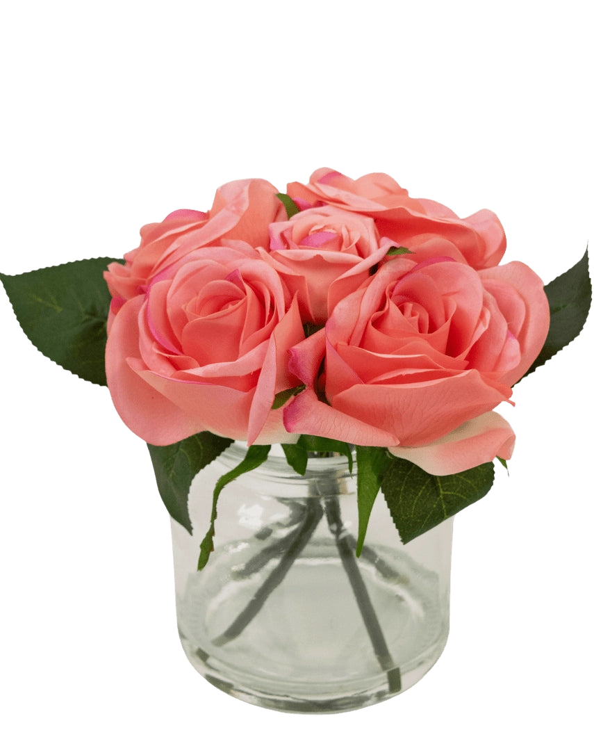 Il bouquet di rose artificiali Real Touch Pink da 18 cm è composto da piccole rose artificiali rosa con foglie verdi in un barattolo di vetro trasparente su uno sfondo bianco.