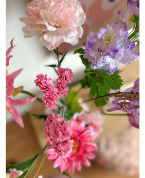 Un primo piano del ramo artificiale Statice rosa da 64 cm, con delicati fiori rosa statice e foglie verdi, disposti in un bouquet su uno sfondo interno delicatamente sbiadito.
