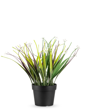 De Kunstplant Grasplant in pot UV 26 cm heeft lange groene en paarse bladeren met kleine witte bloemen, gerangschikt in een eenvoudige zwarte pot en weergegeven tegen een witte achtergrond.