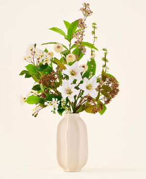 Bouquet di fiori artificiali in seta Timeless Bloom, composto da un bouquet di vari gigli bianchi, piccoli fiori bianchi e verde in un vaso beige con struttura.