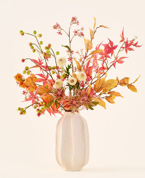 Bouquet di fiori di seta artificiale 'Autumn Breeze' in un vaso di ceramica bianca, con una disposizione di foglie autunnali, piccole bacche verdi, fiori rosa e fiori bianchi, realizzato con fiori di seta di alta qualità. Posizionato su uno sfondo chiaro: il bouquet di fiori artificiali perfetto per conferire a qualsiasi stanza un'atmosfera stagionale di lunga durata.