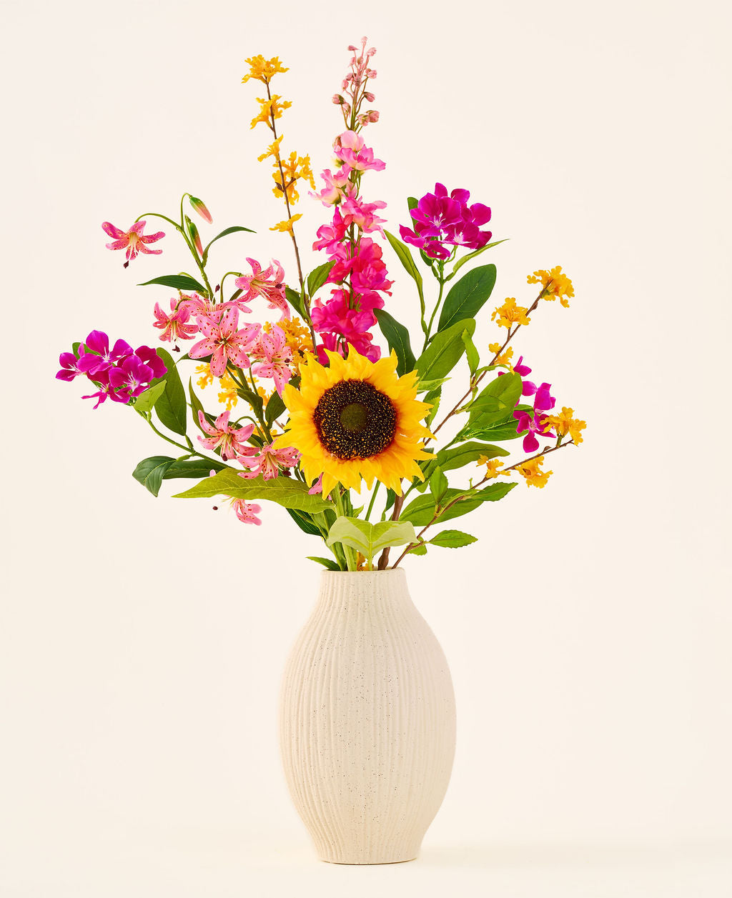 Il bouquet di fiori artificiali in seta "Tiny Sunshine" è posto in un vaso di ceramica beige, composto da un bouquet artificiale di fiori realistici, come un grande girasole, fiori rosa e magenta e fiori gialli con foglie verdi, su uno sfondo chiaro. Questa composizione di Easyplants è composta da bellissimi fiori di seta che aggiungono bellezza duratura a qualsiasi stanza.