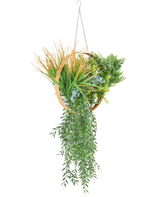 De Kunst hangplant varen UV 30 cm in ring goud heeft verschillende kunstplanten, zoals varens, trapsgewijze wijnranken, stekelig gras en blauwe bloemen, gerangschikt in een gouden ring met een ketting om op te hangen.