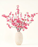 De Zijden kunstbloemen boeket Kersenbloesem fuchsia 150 cm heeft levendige fuchsia kersenbloesem stelen met groene bladeren in een eenvoudige witte vaas, die een aanvulling is op elk interieur tegen een lichte achtergrond.