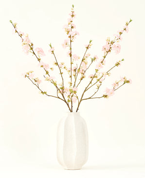 Il bouquet di fiori artificiali in seta Fiore di ciliegio rosa chiaro 94 cm presenta delicati fiori di ciliegio artificiali rosa in un vaso di ceramica bianca, che aggiunge eleganza su uno sfondo chiaro e semplice.