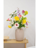 Een Kunstanemoon Real Touch paars 52cm staat op een lichte houten tafel en toont zijn realistische paarse bloemen in een beige vaas tegen een effen witte muur.