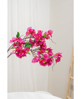 De Kunstbloem Bougainvillea 90 cm paars, met levendige paarse bloemen en groene bladeren, wordt getoond tegen een lichte neutrale achtergrond naast een houten ladder aan de rechterkant.