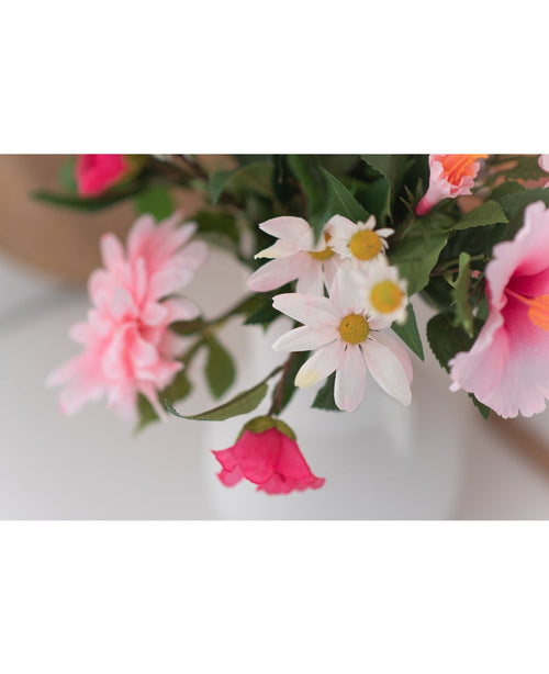 Un primo piano del fiore artificiale Margriet da 60 cm bianco/rosa mostra margherite rosa e bianche con un cuore giallo in un vaso bianco su uno sfondo neutro.