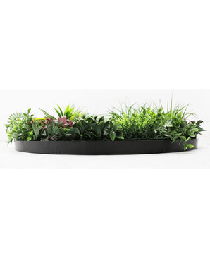 La siepe artificiale su telaio nero Ø100 cm è una fioriera nera semicircolare piena di fogliame verde lussureggiante e alcune foglie rosa, su uno sfondo bianco.