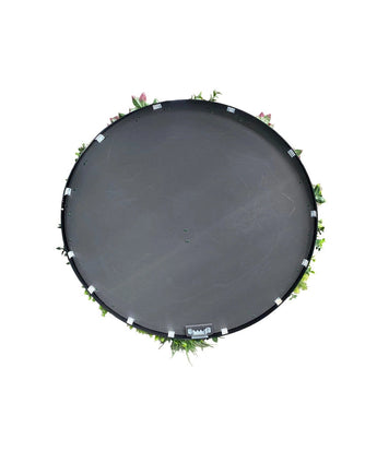 Een Kunsthaag op Zwart Frame Ø100 cm trampoline, van bovenaf gezien met groene bladeren en roze bloemen rond de rand, tegen een witte achtergrond.