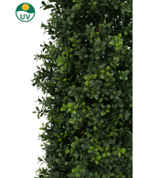 Een close-up van weelderig groen Kunstplant Buxus Pyramide UV 90 cm blad met glanzende bladeren. Een zon- en UV-icoon in de hoek benadrukt de UV-bescherming voor gebruik als tuinplant voor buiten of binnen.