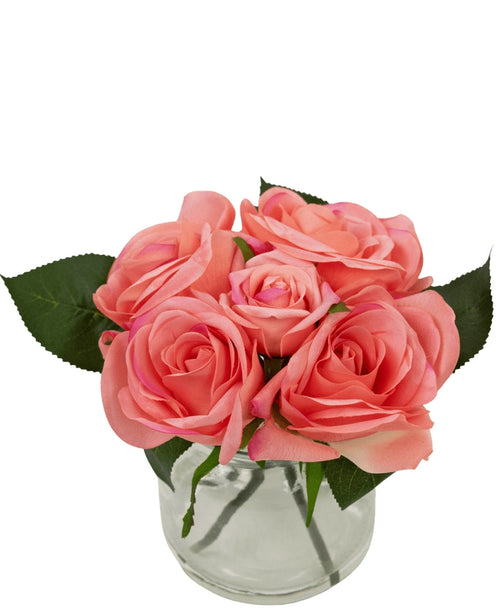 Il bouquet di rose artificiali Real Touch Pink 18 cm è composto da cinque rose artificiali rosa con foglie verdi, ravvicinate in un piccolo vaso di vetro con acqua, su uno sfondo bianco.