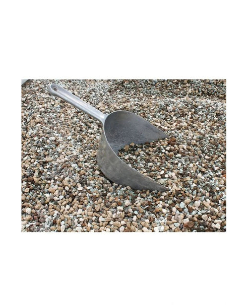 Una pala di metallo è parzialmente sepolta in un mucchio di ciottoli vulcanici contenuti in un sacco da 10 litri.