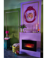 Een moderne woonkamer met groene muren, een paarse open haard en roze ingelijste luipaardkunst. Een mand met een deken, Zijden kunstboeket Tulpen in vaas Paars en kaarsen versieren de ruimte. Boeken en een roze lamp staan op een groenblauwe bijzettafel.