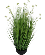 De Kunstgras Prei Bloem Ui Graspot 100cm brandvertragend is een kunstgrasplant in pot met lange, slanke sprieten en kleine witte bloemtrosjes in een zwarte ronde pot, afgebeeld tegen een effen witte achtergrond.