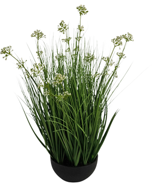 De Kunstgras Prei Bloem Ui Graspot 60cm brandvertragend heeft hoge, dunne grasachtige groene bladeren met kleine witte bloemtrosjes in een zwarte pot, tegen een witte achtergrond.