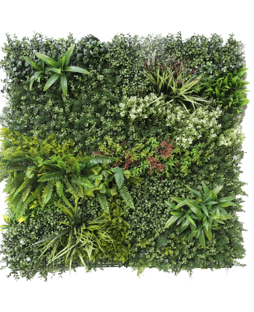 La siepe artificiale Prestige 100x100 cm UV è un pannello quadrato di fogliame verde artificiale con piante miste a foglia, felci, texture varie e sfumature di verde, oltre a grappoli di piccoli fiori bianchi e rossi. Lo sfondo è bianco.