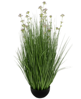 De Kunstgras Prei Bloem Ui Graspot 100cm brandvertragend heeft een zwarte pot met hoge, dunne groene kunstbladeren en kleine paarse bloemen op lange stelen, tegen een witte achtergrond.